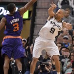 San Antonio Spurs guard Tony Parker (9), of France, passes around Phoenix Suns guard Brandon Knight during the first half of an NBA basketball game, Wednesday, Dec. 30, 2015, in San Antonio. (AP Photo/Darren Abate)