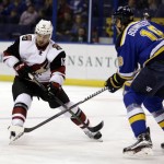 Arizona Coyotes' Brad Richardson, left, chases after the puck as St. Louis Blues' Jay Bouwmeester watches during the first period of an NHL hockey game Tuesday, Dec. 8, 2015, in St. Louis. (AP Photo/Jeff Roberson)