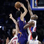 Phoenix Suns guard Devin Booker shoots over the defense of Detroit Pistons center Aron Baynes (12) and forward Anthony Tolliver during the first half of an NBA basketball game, Wednesday, Dec. 2, 2015, in Auburn Hills, Mich. (AP Photo/Carlos Osorio)