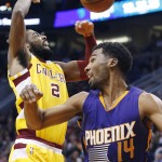Cleveland Cavaliers' Kyrie Irving (2) gets fouled by Phoenix Suns' Ronnie Price (14) as he goes up for a shot during the first half of an NBA basketball game Monday, Dec. 28, 2015, in Phoenix. (AP Photo/Ross D. Franklin)