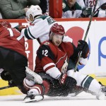 Arizona Coyotes' Brad Richardson (12), Steve Downie (17) and Minnesota Wild's Nino Niederreiter (22), of Switzerland, collide as they all go after the puck during the second period of an NHL hockey game Friday, Dec. 11, 2015 in Glendale, Ariz. (AP Photo/Ross D. Franklin)