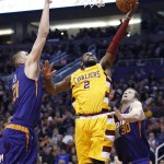Cleveland Cavaliers' Kyrie Irving (2) drives past Phoenix Suns' Jon Leuer (30) and Alex Len (21), of Ukraine, to score during the first half of an NBA basketball game Monday, Dec. 28, 2015, in Phoenix. (AP Photo/Ross D. Franklin)