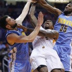 Phoenix Suns' Eric Bledsoe, center, finds his way to the basket blocked by Denver Nuggets' Kenneth Faried (35) and Kostas Papanikolaou, left, of Greece, during the first half of an NBA basketball game Wednesday, Dec. 23, 2015, in Phoenix. (AP Photo/Ross D. Franklin)