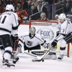 Los Angeles Kings' Brayden McNabb (3) tries to clear the puck away from  Arizona Coyotes' Viktor Tikhonov, second from left, as Kings goalie Jonathan Quick (32) and Anze Kopitar (11) watch the puck during the third period of an NHL hockey game, Saturday, Dec. 26, 2015, in Glendale, Ariz. The Kings defeated the Coyotes 4-3 in overtime. (AP Photo/Ralph Freso)