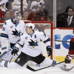 San Jose Sharks' Logan Couture, middle, deflects the puck in front of goalie Martin Jones (31) on a shot from Arizona Coyotes' Jordan Martinook, right, during the first period of an NHL hockey game Thursday, Jan. 21, 2016, in Glendale, Ariz. The Sharks won 3-1. (AP Photo/Ross D. Franklin)