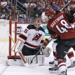 New Jersey Devils goalie Cory Schneider, left, makes a pad save on the shot by Arizona Coyotes' Jordan Martinnok (48) as the Devils' Jon Merrill defends during the third period of an NHL hockey game, Saturday, Jan. 16, 2016, in Glendale, Ariz. The Devils defeated the Coyotes 2-0. (AP Photo/Ralph Freso)