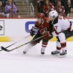 Arizona Coyotes' Max Domi, left, has the puck knocked away by New Jersey Devils' Jon Merrill during the first period of an NHL hockey game, Saturday, Jan. 16, 2016, in Glendale, Ariz. (AP Photo/Ralph Freso)