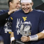 West Virginia's Skyler Howard, right, laughs as he holds the Offensive Player Of The Game trophy as head coach Dana Holgorsen, left, slaps Howard's shoulder after the Cactus Bowl NCAA college football game against Arizona State on Sunday, Jan. 3, 2016, in Phoenix. West Virginia won 43-42. (AP Photo/Ross D. Franklin)