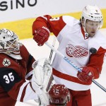 Detroit Red Wings' Justin Abdelkader (8) has the puck deflect off his shoulder as Arizona Coyotes' Louis Domingue (35) moves in to make a save during the first period of an NHL hockey game Thursday, Jan. 14, 2016, in Glendale, Ariz. (AP Photo/Ross D. Franklin)