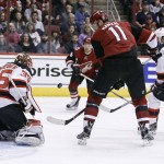 New Jersey Devils goalie Corey Schneider (35) has the puck deflected off his blocker after a save as Arizona Coyotes' Martin Hanzal (11), of the Czech Republic, looks for a scoring opportunity off the rebound during the first period of an NHL hockey game, Saturday, Jan. 16, 2016, in Glendale, Ariz. (AP Photo/Ralph Freso)