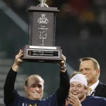 West Virginia head coach Dana Holgorsen, left, holds up the championship trophy as quarterback Skyler Howard applauds after the Cactus Bowl NCAA college football game against Arizona State, Sunday, Jan. 3, 2016, in Phoenix. West Virginia won 43-42. (AP Photo/Ross D. Franklin)