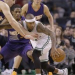 Boston Celtics guard Isaiah Thomas, front left, passes to a teammate behind him while driving toward the hoop as he runs into Phoenix Suns defenders during the second half of their NBA basketball game Friday, Jan. 15, 2016, in Boston. The Celtics defeated the Suns 117-103. (AP Photo/Stephan Savoia)