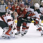 New Jersey Devils goalie Cory Schneider, left, positions himself for a save as Arizona Coyotes' Brad Richardson (12) and the Devils' David Schlemko (8) battle for the puck in front of the net during the third period of an NHL hockey game, Saturday, Jan. 16, 2016, in Glendale, Ariz. The Devils defeated the Coyotes 2-0. (AP Photo/Ralph Freso)