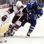 Vancouver Canucks defenseman Matt Bartkowski (44) fights for control of the puck with Arizona Coyotes left wing Anthony Duclair (10) during first period NHL hockey action in Vancouver, British Columbia, Canada, Monday, Jan. 4, 2016. (Jonathan Hayward/The Canadian Press via AP)