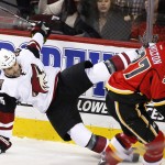 Arizona Coyotes' Boyd Gordon, left, is knocked off his skates by Calgary Flames' Dennis Wideman, not seen, as Flames' Dougie Hamilton skates past during the third period of an NHL hockey game Thursday, Jan. 7, 2015, in Calgary, Alberta. (Larry MacDougal/The Canadian Press via AP)