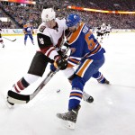 Arizona Coyotes' Michael Stone (26) and Edmonton Oilers' Benoit Pouliot (67) battle for the puck during second period NHL action in Edmonton, Alberta, on Saturday, Jan. 2, 2016. (Jason Franson/The Canadian Press via AP)