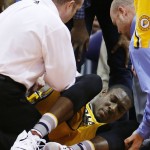 An injured Indiana Pacers' Ian Mahinmi, of France, is attended to by training staff during the first half of an NBA basketball game against the Phoenix Suns, Tuesday, Jan. 19, 2016, in Phoenix. (AP Photo/Ross D. Franklin)
