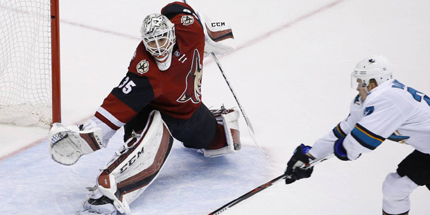 Arizona Coyotes' Louis Domingue, left, moves into position to make a save on a shot by San Jose Sha...