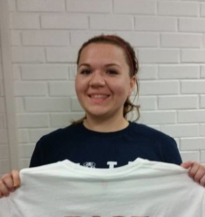 Madison O'Neal holds up a shirt from the non-profit she started, Bringing Athletes Sports Equipment...