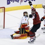 Arizona Coyotes' Martin Hanzal (11), of the Czech Republic, celebrates a goal by  teammate Oliver Ekman-Larsson (not shown) against Calgary Flames' Jonas Hiller (1), of Switzerland, as Flames' Mark Giordano (5) looks on during the second period of an NHL hockey game Friday, Feb. 12, 2016, in Glendale, Ariz. (AP Photo/Ross D. Franklin)
