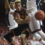 Southern California guard Jordan McLaughlin, middle, passes the ball between Arizona guard Allonzo Trier and Ryan Anderson (12) during the first half of an NCAA college basketball game, Sunday, Feb. 14, 2016, in Tucson, Ariz. (AP Photo/Rick Scuteri)