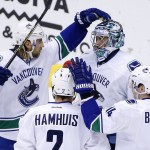 Vancouver Canucks' Ryan Miller, top right, celebrates the team's 2-1 win against the Arizona Coyotes with Dan Hamhuis (2), Alex Burrows (14) and Chris Tanev, left, after an NHL hockey game Wednesday, Feb. 10, 2016, in Glendale, Ariz. (AP Photo/Ross D. Franklin)