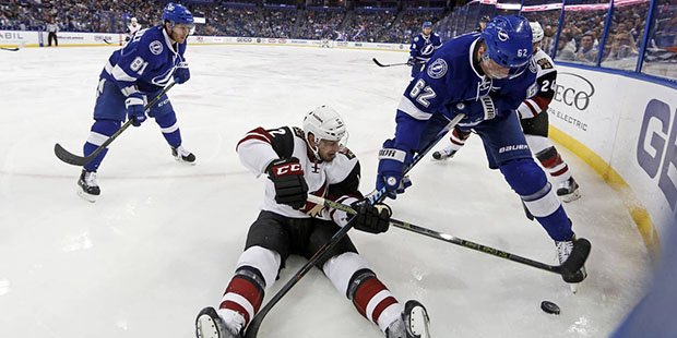 Arizona Coyotes' Brad Richardson tries to maintain control of the puck as he's checked by Tampa Bay...