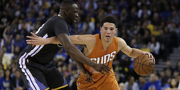 Phoenix Suns' Devin Booker, right, drives the ball against Golden State Warriors' Draymond Green du...