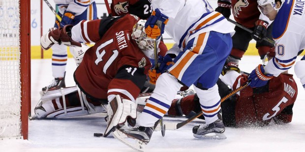 The puck gets past Arizona Coyotes' Mike Smith (41) as Edmonton Oilers' Jordan Eberle, middle, gets...