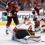 Calgary Flames goalie Joni Ortio, middle, of Finland, makes a save on a shot by Arizona Coyotes' Anthony Duclair (10) as Flames' Derek Grant (57) defends against Coyotes' Brad Richardson (12) during the second period of an NHL hockey game Monday, March 28, 2016, in Glendale, Ariz. (AP Photo/Ross D. Franklin)