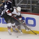 Arizona Coyotes left wing Sergei Plotnikov, front, of Russia, drives Colorado Avalanche defenseman Zach Redmond into the boards to take control of the puck in the first period of an NHL hockey game, Monday, March 7, 2016, in downtown Denver. (AP Photo/David Zalubowski)