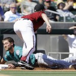 Arizona Diamondbacks pitcher Zack Greinke, top, tags out Seattle Mariners' Shawn O'Malley at third base during the third inning of a spring training baseball game in Scottsdale, Ariz., Monday, March 14, 2016. (AP Photo/Jeff Chiu)