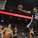 Golden State Warriors' Stephen Curry (30) lays up a shot against Phoenix Suns' Eric Bledsoe, left, and Devin Booker (1) during the first half of an NBA basketball game Saturday, March 12, 2016, in Oakland, Calif. (AP Photo/Ben Margot)