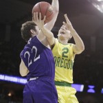 Oregon guard Casey Benson (2) is fouled by Holy Cross guard Robert Champion (22) as he shoots during the first half of a first-round men's college basketball game in the NCAA Tournament in Spokane, Wash., Friday, March 18, 2016. (AP Photo/Young Kwak)