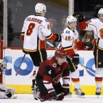 Calgary Flames' Sean Monahan (23) celebrates his goal against Arizona Coyotes' Louis Domingue (35) with Hunter Shinkaruk (49) and Joe Colborne (8) as Coyotes' Zbynek Michalek (4), of the Czech Republic, kneels on the ice during the second period of an NHL hockey game Monday, March 28, 2016, in Glendale, Ariz. (AP Photo/Ross D. Franklin)