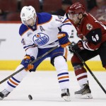 Edmonton Oilers' Jordan Eberle (14) tries to control the puck in front of Arizona Coyotes' Jordan Martinook (48) during the first period of an NHL hockey game, Tuesday, March 22, 2016, in Glendale, Ariz. (AP Photo/Ross D. Franklin)