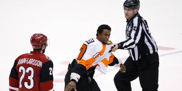Philadelphia Flyers' Wayne Simmonds (17) is restrained by linesman Greg Devorski (54) as he tries t...