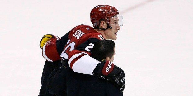 Arizona Coyotes' Michael Stone is helped off the ice after injuring his leg during the third period...