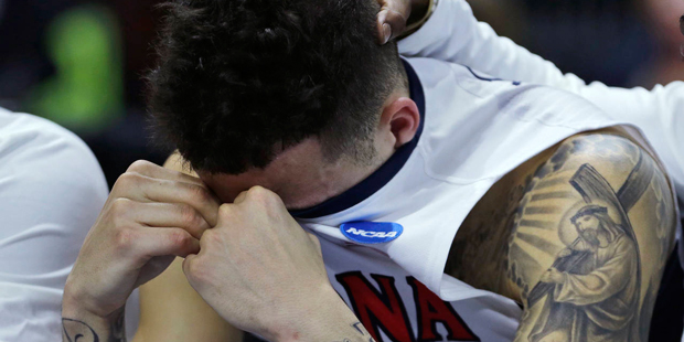 Arizona guard Gabe York hides his emotions as a teammate rests his hand on his head in the closing ...