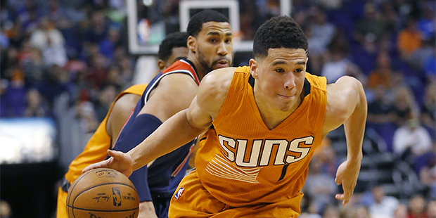 Phoenix Suns guard Devin Booker (1) drives against Washington Wizards guard Garrett Temple, rear,  ...