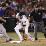 Arizona Diamondbacks' Jake Lamb, middle, snags a grounder hit by Colorado Rockies' Cristhian Adames as Rockies' Nick Hundley (4) gets back to third base and umpire Tim Timmons signals a fair ball during the eighth inning of a baseball game Friday, April 29, 2016, in Phoenix. Adames was out at first base on Lamb's throw. (AP Photo/Ross D. Franklin)