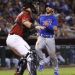 Chicago Cubs Tommy La Stella (2) scores on an RBI double by teammate Miguel Montero during the fourth inning of a baseball game as Arizona Diamondbacks catcher Chris Herrmann waits for the throw, Sunday, April 10, 2016, in Phoenix. (AP Photo/Matt York)