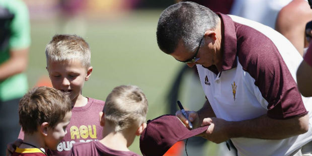Arizona State head coach Todd Graham, right, gives autographs to young fans during a spring NCAA co...