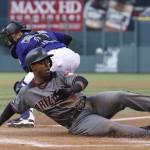 Arizona Diamondbacks' Jean Segura, front, slides safely across home plate to score on a sacrifice fly hit by Paul Goldschmidt as Colorado Rockies catcher Tony Wolters fields the throw from the outfield in the first inning of a baseball game, Monday, May 9, 2016, in Denver. (AP Photo/David Zalubowski)