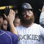 Colorado Rockies' Charlie Blackmon is congratulated by teammates after scoring with Mark Reynolds on a double hit by Ryan Raburn off Arizona Diamondbacks relief pitcher Evan Marshall in the sixth inning of a baseball game Wednesday, May 11, 2016, in Denver. (AP Photo/David Zalubowski)