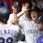 Colorado Rockies' Nolan Arenado, left, celebrates his run scored against the Arizona Diamondbacks with Daniel Descalso, right, Nick Hundley, second from right, and Eddie Butler, second from left, during the fourth inning of a baseball game, Sunday, May 1, 2016, in Phoenix. (AP Photo/Ross D. Franklin)