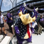 In this view through a fisheye lens, Colorado Rockies mascot Dinger the dinosaur, in U.S. flag design to mark the Memorial Day holiday, heads off the diamond for the start of the first inning of a baseball game against the Cincinnati Reds on Monday, May 30, 2016, in Denver. (AP Photo/David Zalubowski)