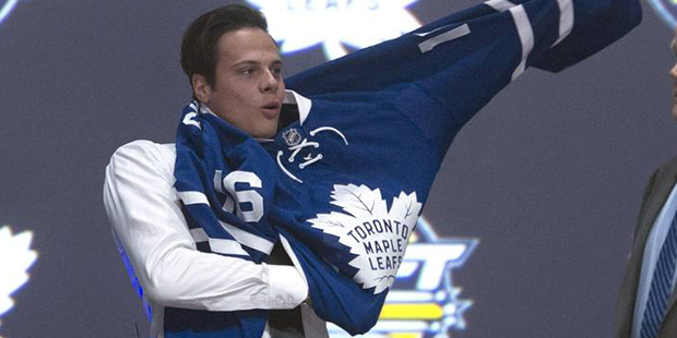 Toronto Maple Leafs first overall pick Auston Matthews, center, pulls on his sweater as he stand wi...