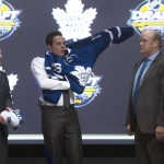 Toronto Maple Leafs first overall pick Auston Matthews, center, pulls on his sweater as he stand with members of the Maple Leafs management team at the NHL draft in Buffalo, N.Y., Friday June 24, 2016. (Nathan Denette/The Canadian Press via AP) MANDATORY CREDIT