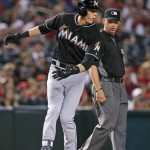 Miami Marlins' Christian Yelich stops after skidding past third base on a triple against the Arizona Diamondbacks as umpire Will Little watches during the first inning of a baseball game Friday, June 10, 2016, in Phoenix. (AP Photo/Ross D. Franklin)